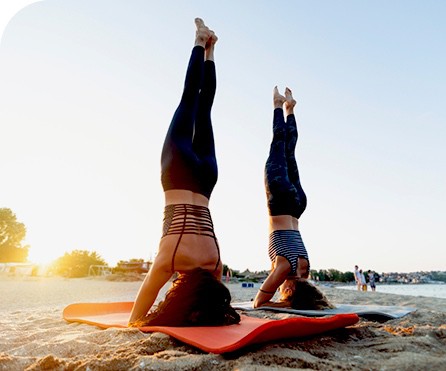 Two women do yoga on the beach